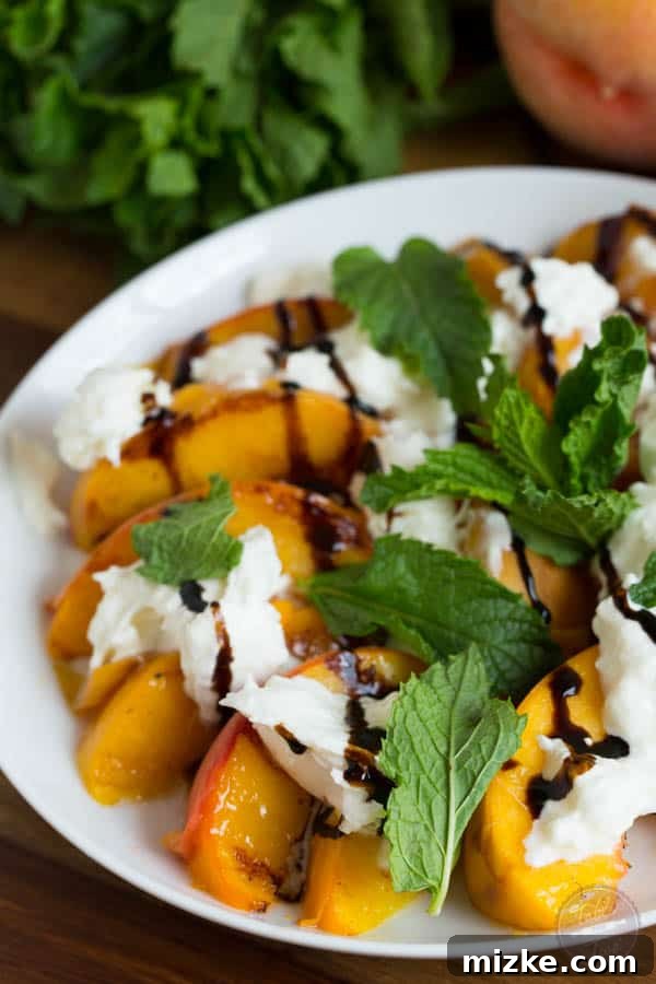 Caramelized Peach Burrata Bliss 5 A beautifully plated serving of grilled peaches with burrata, fresh mint sprigs, and a dark balsamic glaze, emphasizing its gourmet appeal.