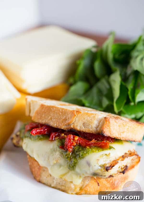 Grilled chicken breasts coated in pesto, topped with slices of Land O Lakes Sharp Cheddar American Blend, ready for melting.