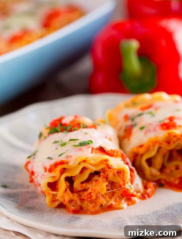 Gourmet Chicken and Roasted Red Pepper Lasagna Pinwheels 2 Freshly prepared Roasted Red Pepper Chicken Lasagna Rolls in a baking dish, ready for the oven.