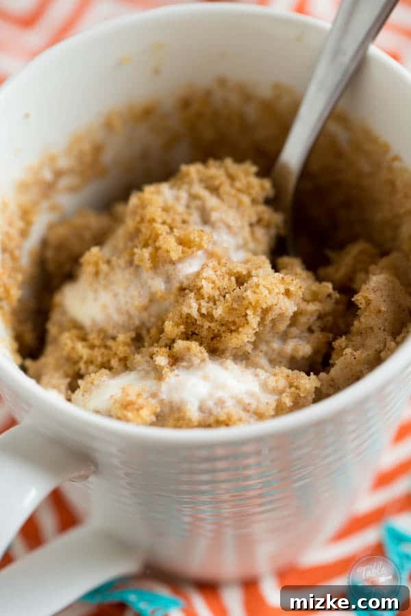 Close-up of a pumpkin spice mug cake, showcasing its moist texture and rich autumnal color, waiting for toppings.
