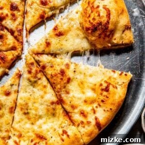 White pizza with golden crust on a round metal tray, partially sliced with one slice pulled away, showing melted cheese strands.