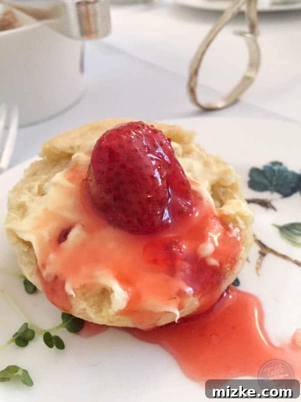 The Perfect Scone Moment A delicious scone being spread with clotted cream and strawberry jam