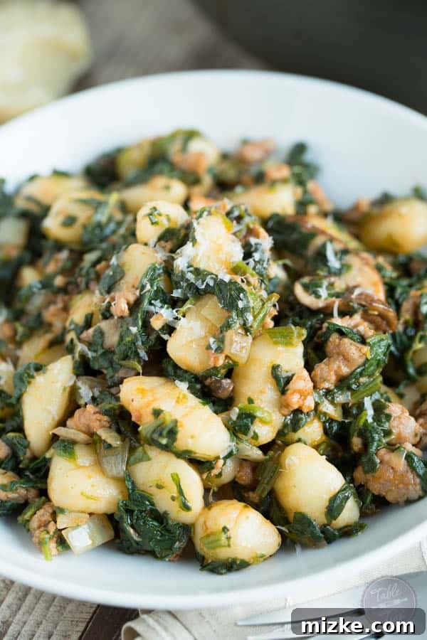 Rustic Spicy Sausage Gnocchi with Spinach and Mushrooms 5 A vibrant bowl of spicy sausage, spinach, and mushroom gnocchi with parmesan cheese, ready to be enjoyed, highlighting the rich colors and enticing textures of a quick home-cooked meal.