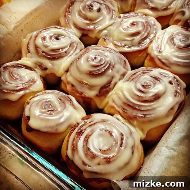 Warm, gooey Cinnabon-style cinnamon rolls with generous cream cheese frosting, fresh from the oven, beautifully arranged.