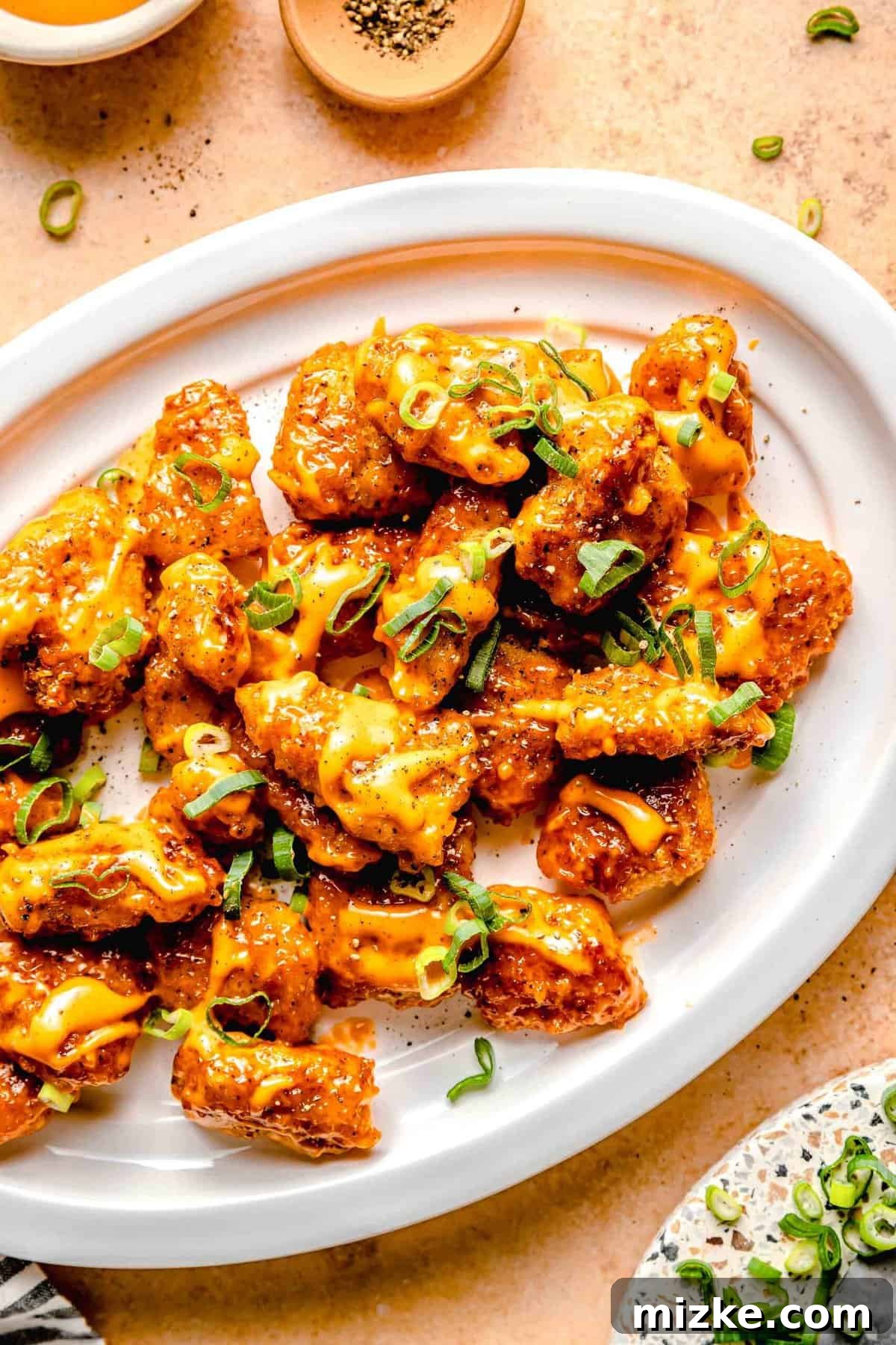 This bang bang chicken dish really lives up to its name. It is A large serving platter beautifully arranged with many pieces of Bang Bang Chicken, garnished with fresh green herbs, indicating a complete and inviting dish ready for serving.