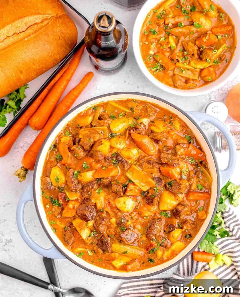 Hearty Slow Cooker Guinness Beef Stew 2 Rich Guinness beef stew in a large pot with a serving bowl beside it, surrounded by fresh ingredients used in the recipe, illustrating its rustic charm and deliciousness.