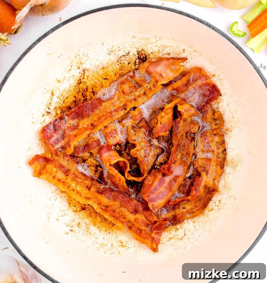 Hearty Slow Cooker Guinness Beef Stew 5 Crispy bacon sizzling in a heavy cast iron skillet, rendered to perfection, ready to infuse its savory flavor into the stew base.