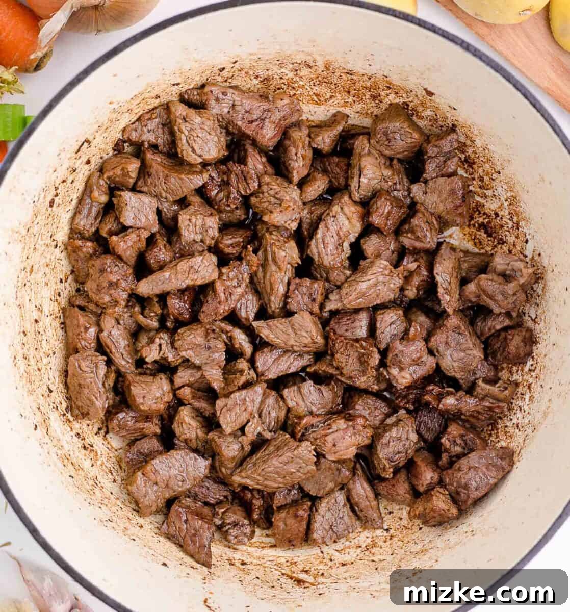 Hearty Slow Cooker Guinness Beef Stew 6 Cubed chuck roast, beautifully browned on all sides, nestled in a cast iron skillet, showcasing the crucial searing step for rich flavor development.