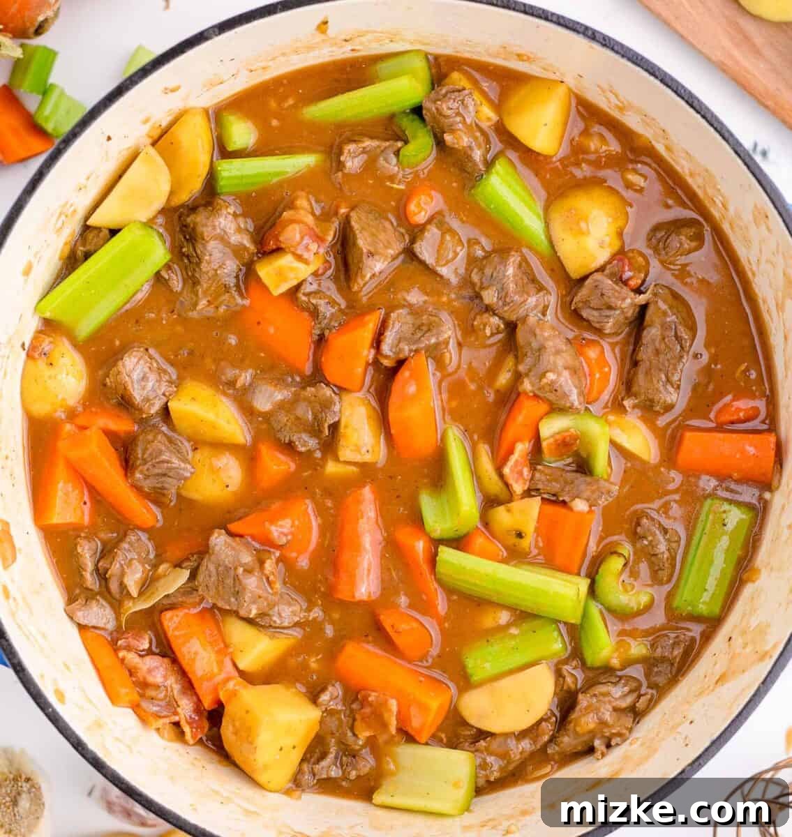 Hearty Slow Cooker Guinness Beef Stew 8 All the hearty ingredients for Guinness beef stew, including vegetables, beef, and liquids, stirred together in a cast iron skillet, ready for slow cooking.