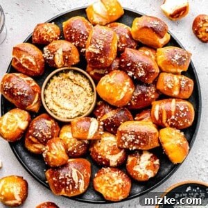 Pretzel bites on a plate with whole-grain mustard, showcasing their golden-brown color and coarse salt topping.