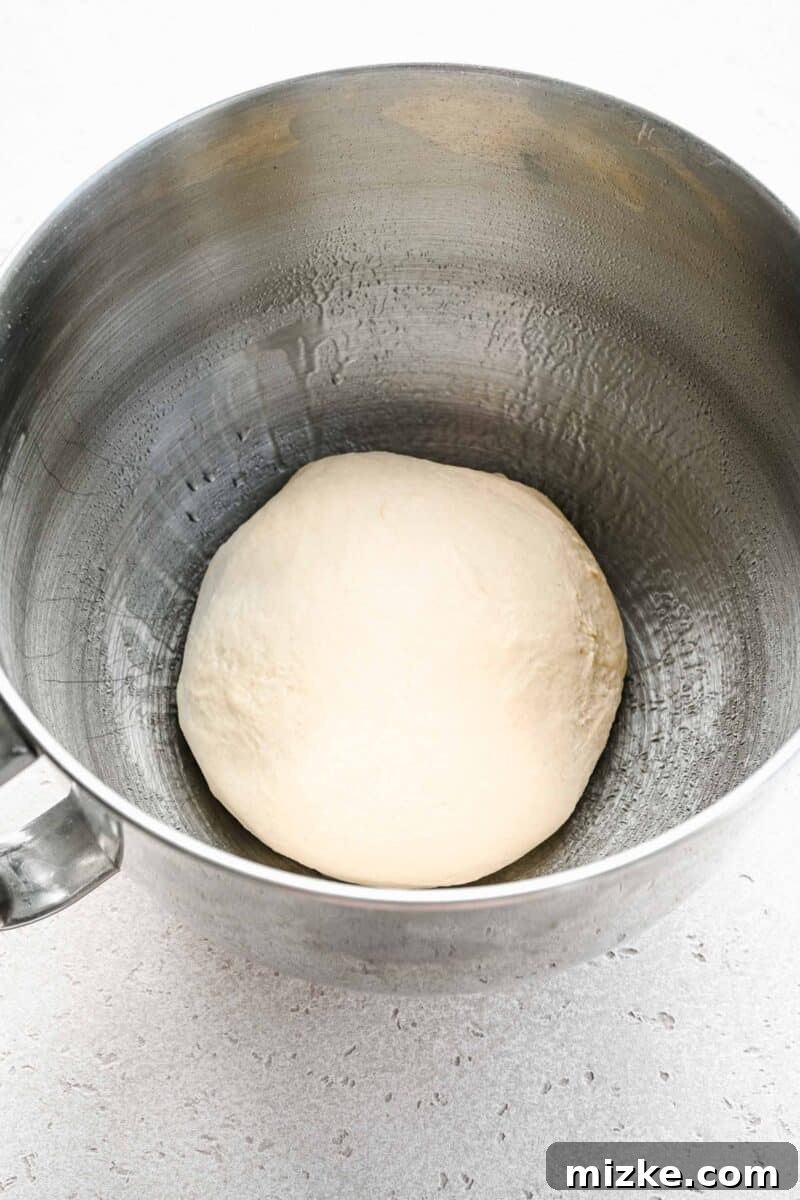 Freshly kneaded pretzel dough resting in a mixing bowl before rising.