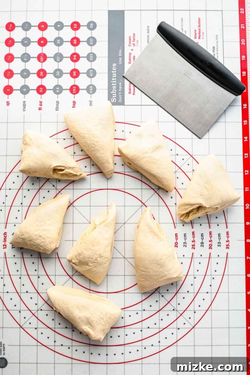 Pretzel dough divided into small, uniform pieces and lined up on a cutting board, ready for boiling.