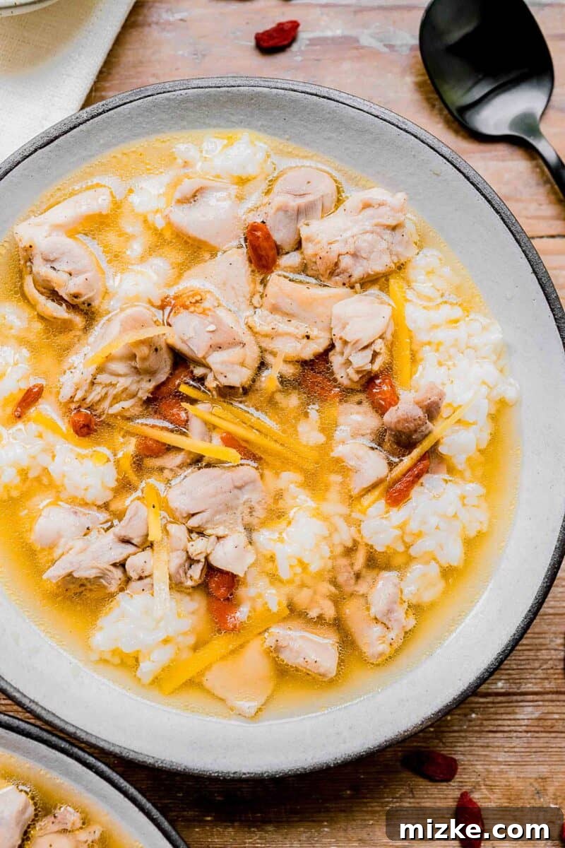 Soul-Warming Rice Wine Chicken Soup 4 A beautifully presented bowl of Drunken Chinese Chicken Soup with rice, showcasing the vibrant colors of the broth and ingredients.
