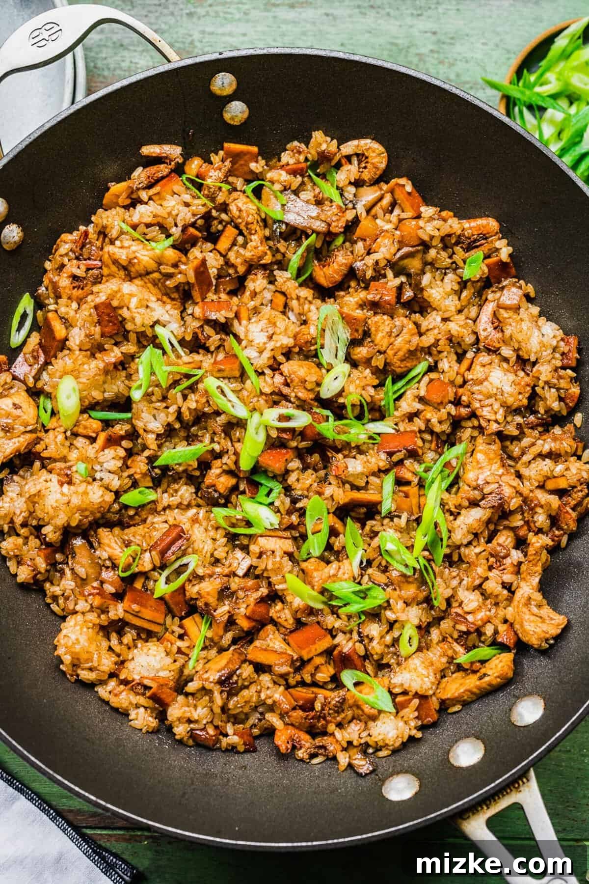 Sticky rice in skillet with sliced scallions
