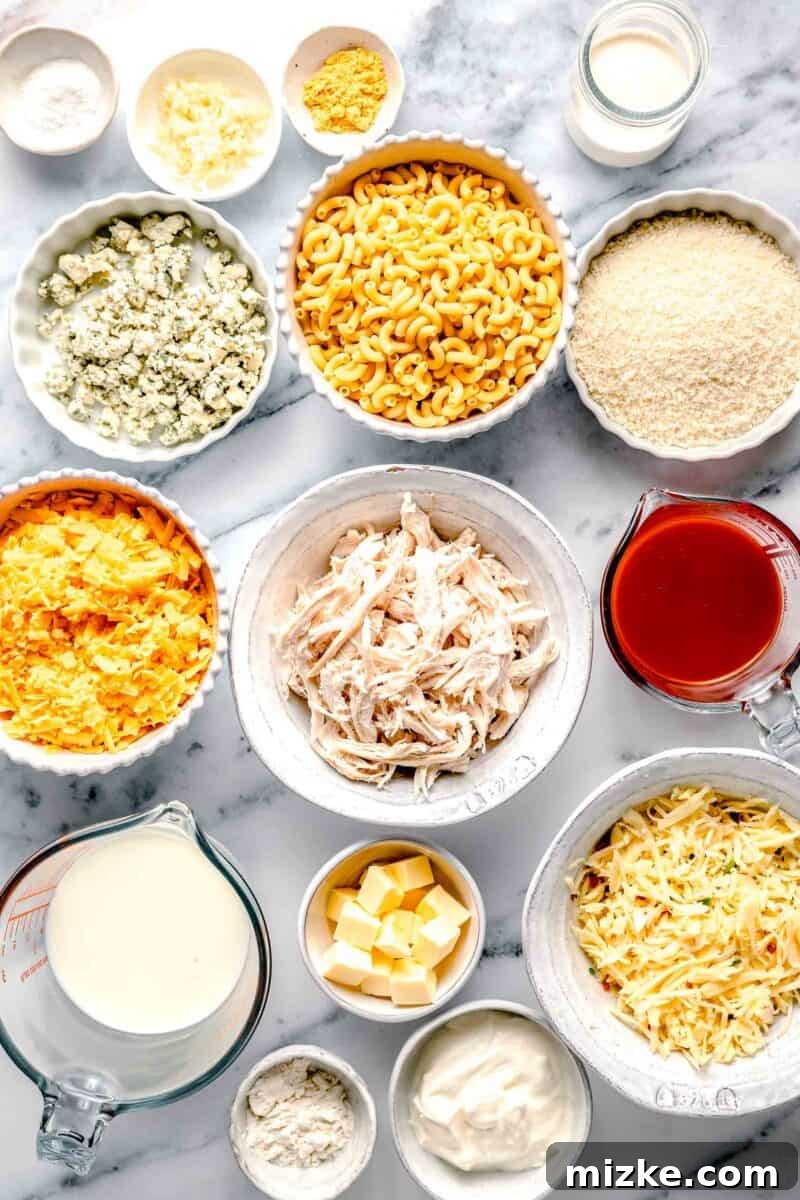 Kickin' Buffalo Mac and Cheese 3 A selection of fresh ingredients for Buffalo Chicken Mac and Cheese, including cheeses, milk, butter, pasta, and spices, neatly arranged on a pristine marble countertop.
