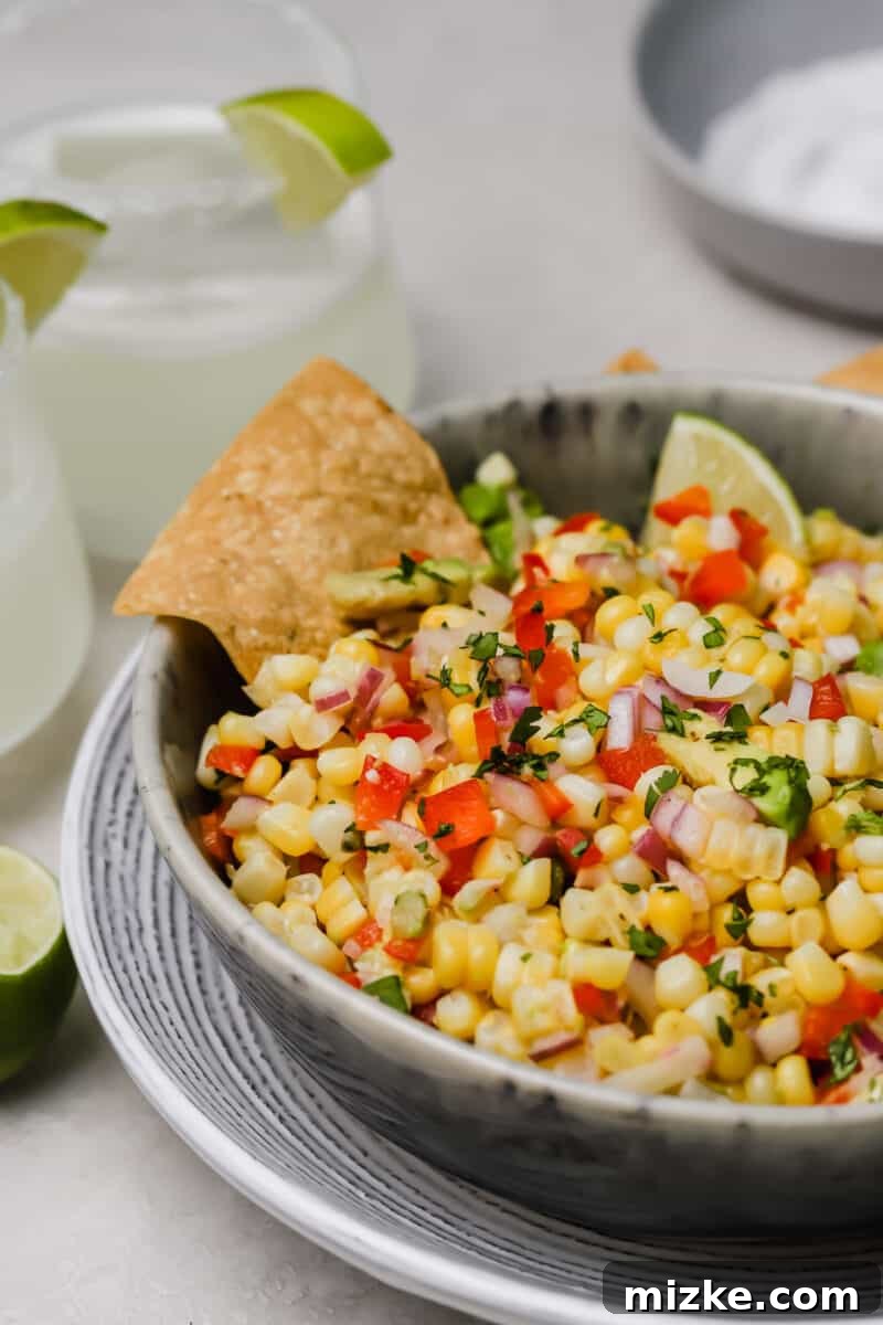 Zesty Corn and Avocado Salsa 5 A large serving bowl filled with homemade corn and avocado salsa, garnished with fresh herbs, ready for a party or family dinner to be enjoyed by everyone.