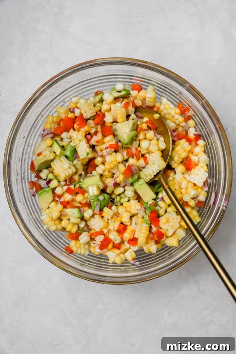 Zesty Corn and Avocado Salsa 6 Fresh ingredients for corn and avocado salsa laid out on a clean wooden cutting board: vibrant corn kernels, ripe avocado, crisp red bell pepper, finely diced red onion, and a fresh lime.