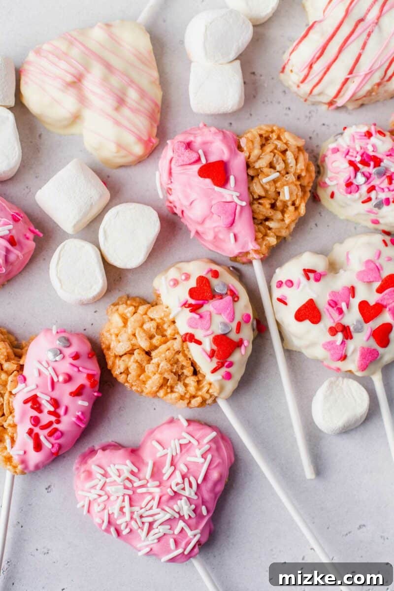 Sweetheart Krispy Delights 4 Multiple freshly made heart-shaped Rice Krispies treats are artfully displayed on a neutral gray surface, surrounded by a scattering of miniature marshmallows, highlighting their delightful texture.
