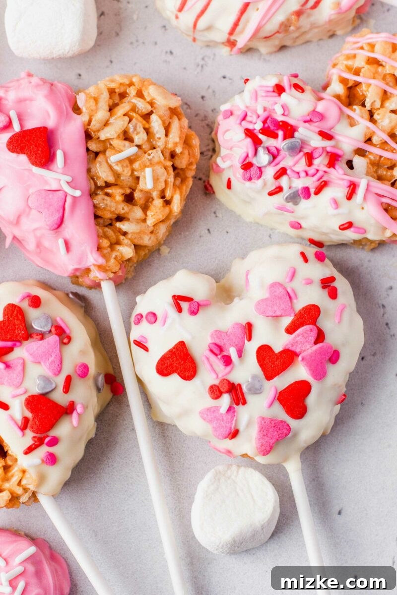 Sweetheart Krispy Delights 5 A single heart-shaped Rice Krispies treat, beautifully covered in white chocolate, is adorned with delicate heart-shaped sprinkles, showcasing its festive Valentine's Day design.