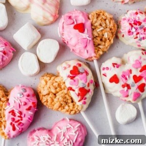 A close-up shot of a heart-shaped Rice Krispie Treat, coated in vibrant pink chocolate and adorned with festive sprinkles.
