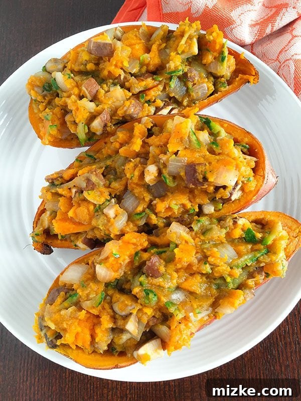 Two whole sweet potatoes, beautifully roasted and sliced open, revealing a vibrant, savory filling of shredded zucchini, mushrooms, and onions. A healthy, hearty, and satisfying meal.