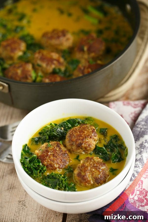 Aromatic Meatball and Kale Curry 3 Close-up of hearty curry meatballs simmering in a rich kale stew, showcasing the inviting textures and colors of this paleo-friendly dish.