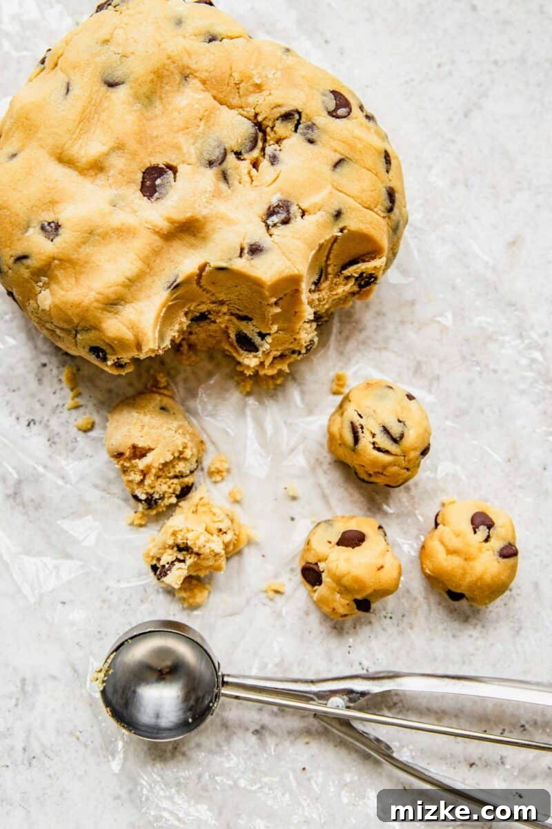 Scooping uniform balls of chocolate chip cookie dough from a large mound of chilled dough.