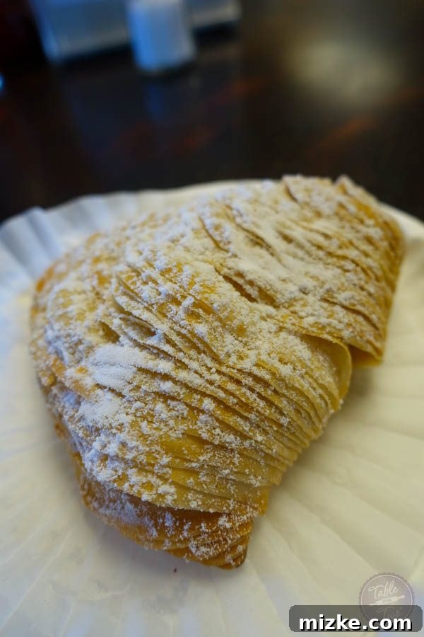 The Enchanting Hudson Valley 32 A close-up of a Sfogliatelle pastry, highlighting its distinctive shell-like layers and powdered sugar dusting.