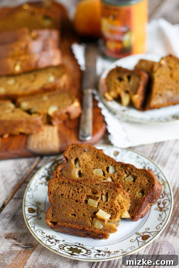 A beautifully sliced loaf of moist Pumpkin Apple Bread, showcasing the warm, inviting colors of autumn baking. Perfect for a cozy fall treat.
