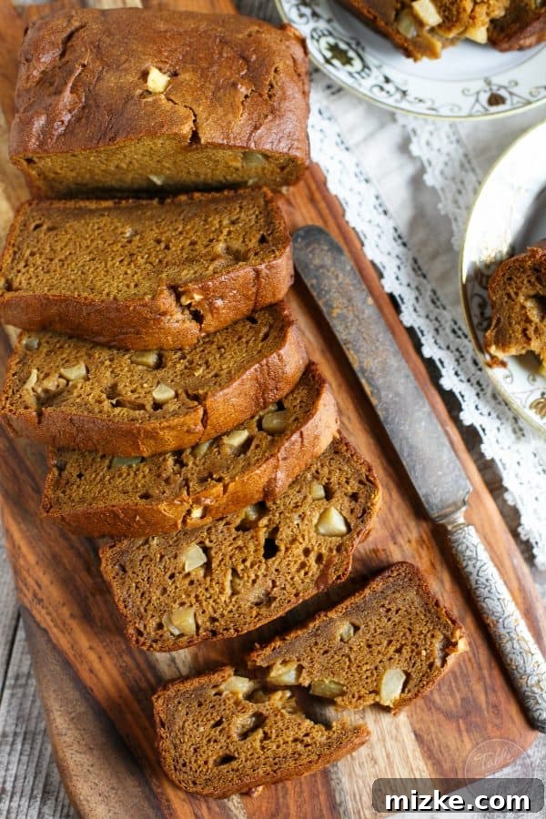 Two golden-brown loaves of freshly baked Pumpkin Apple Bread cooling on a wire rack, ready to be enjoyed. A perfect treat for any fall day.