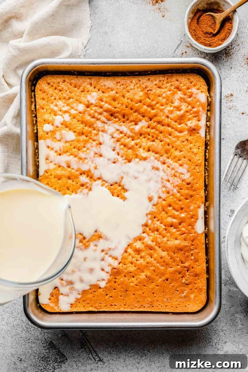 Pouring the essential three-milk mixture onto the sponge cake. Hand pouring the milk mixture over the poked Tres Leches cake in a pan.