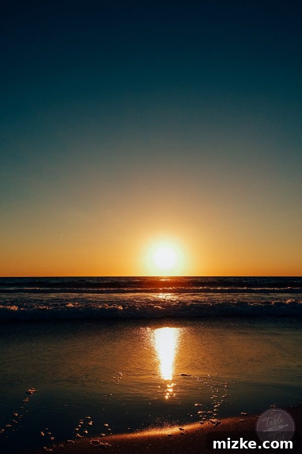 A serene beach scene at sunset, with gentle waves and a colorful sky.