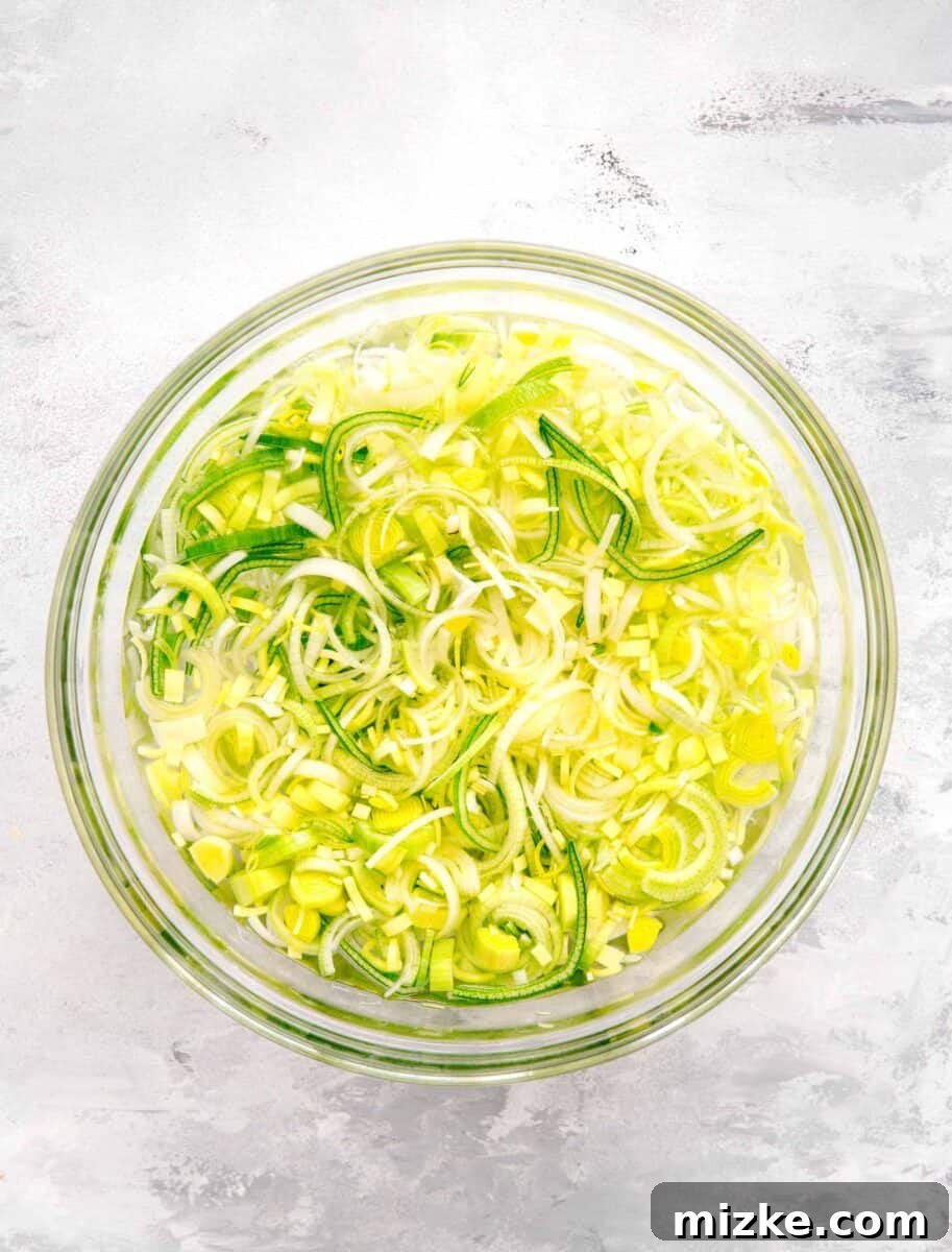 Velvety Mushroom and Leek One-Pot Pasta 5 Sliced leeks soaking in a large clear bowl of cold water, showing the proper cleaning technique.