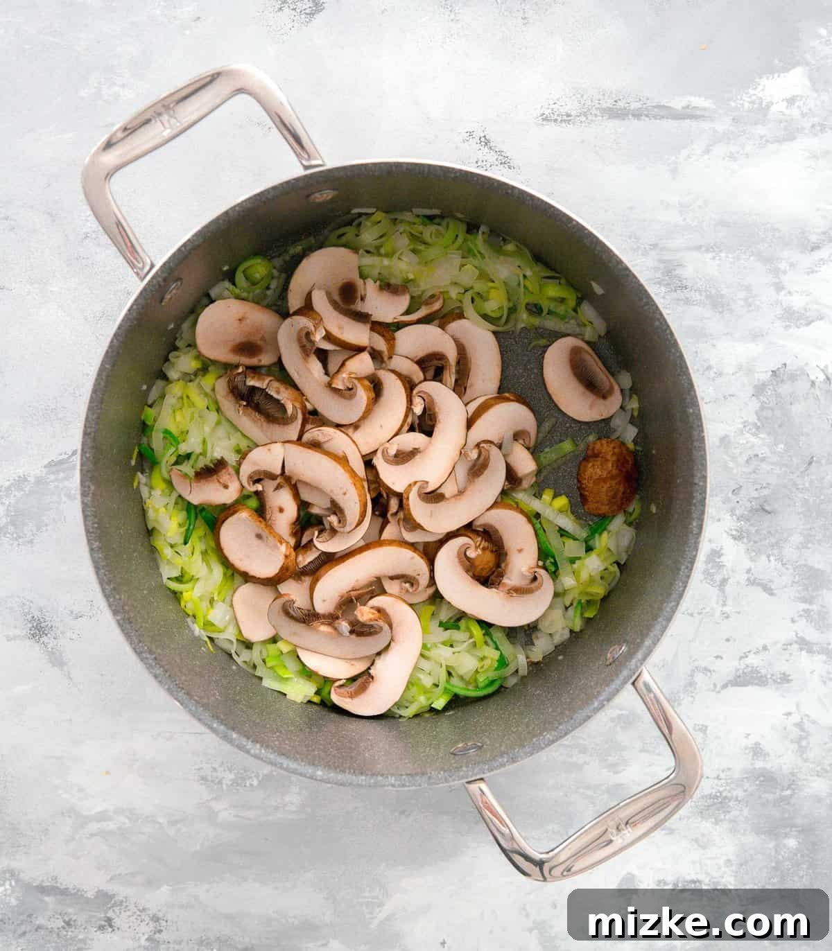 Velvety Mushroom and Leek One-Pot Pasta 7 Sliced mushrooms being added to the pot with softened leeks, onions, and garlic, ready for cooking.