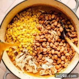Smoky Southwest Chicken Chili 8 Shredded chicken, corn kernels, and pinto beans in a dutch oven with broth being poured over top