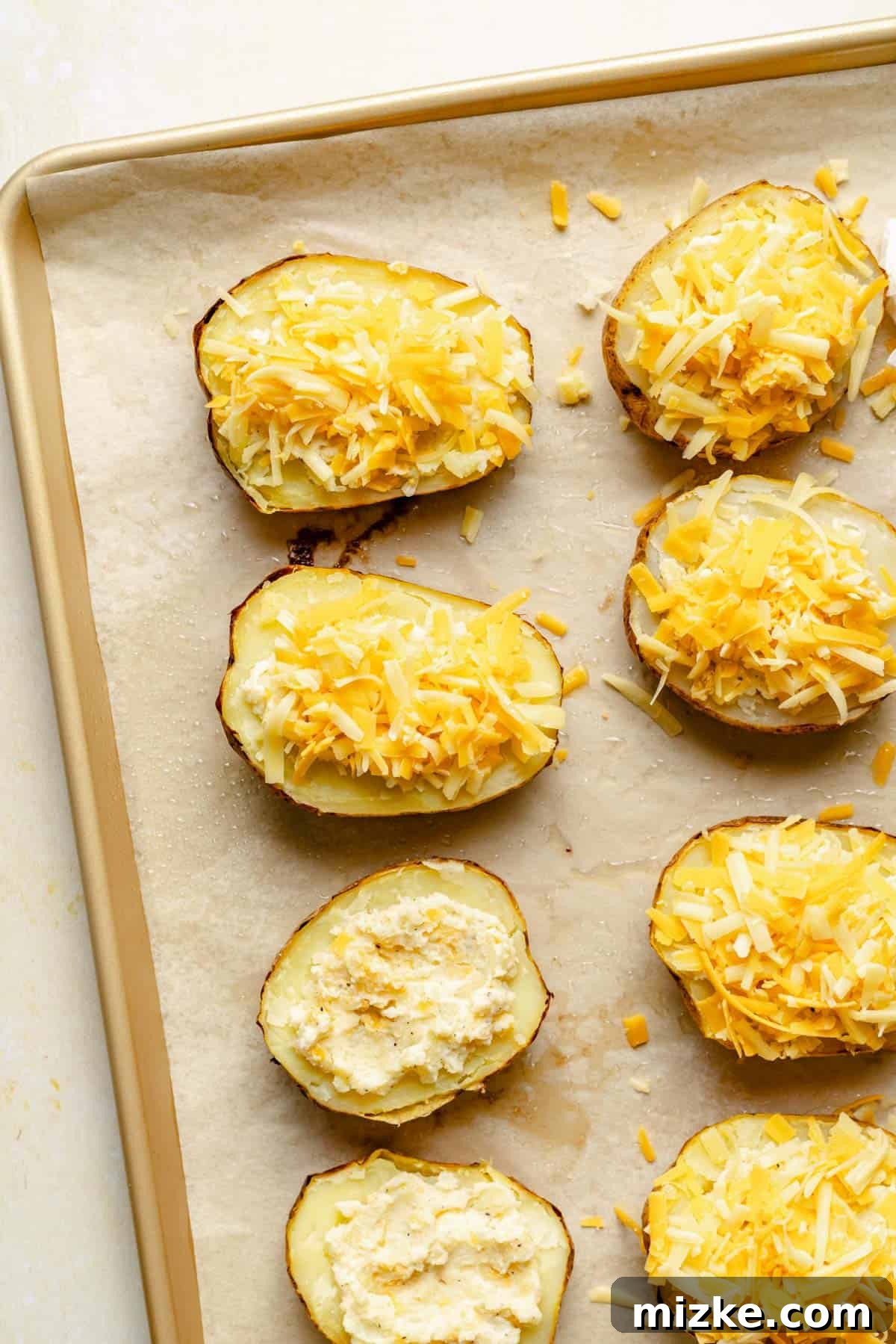 Loaded Double-Baked Potatoes 5 Twice baked potatoes generously topped with shredded cheese, ready for their second bake in the oven.