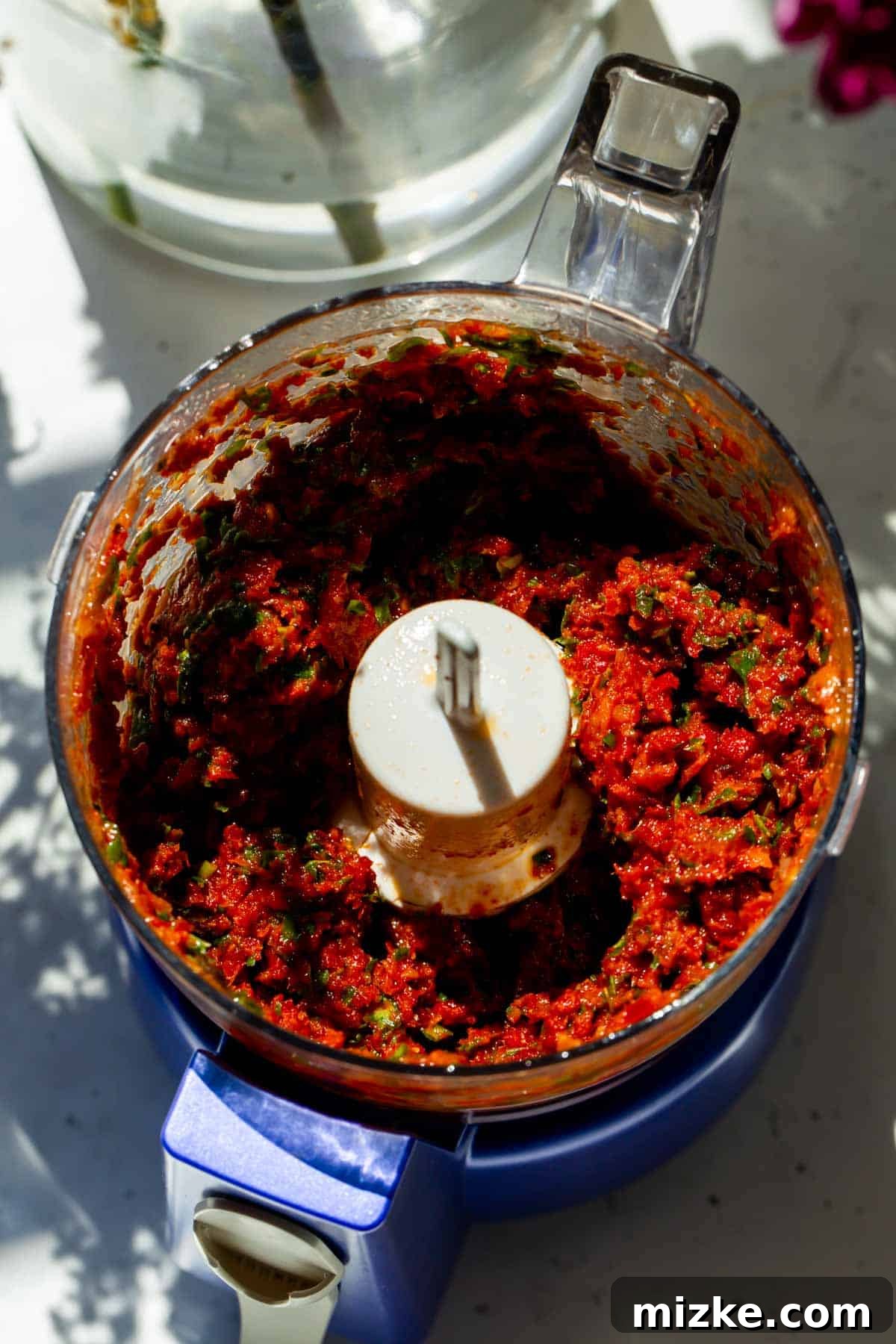 Rich Sun-Dried Tomato Pesto 4 The food processor bowl contains a rich, smooth, and vibrant red sun-dried tomato pesto, expertly blended to a perfect consistency.