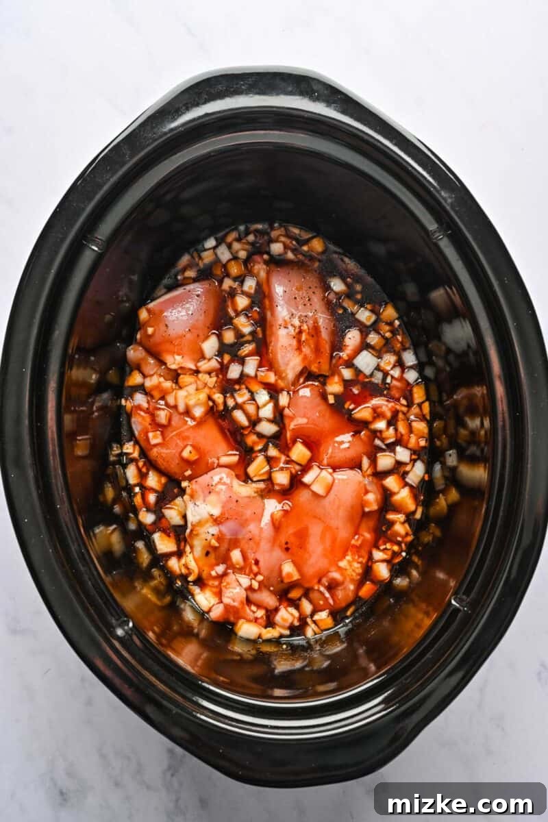Chicken and Sauce Ready for Slow Cooking Seasoned chicken pieces are now generously coated with the freshly prepared honey sesame sauce inside the crockpot.