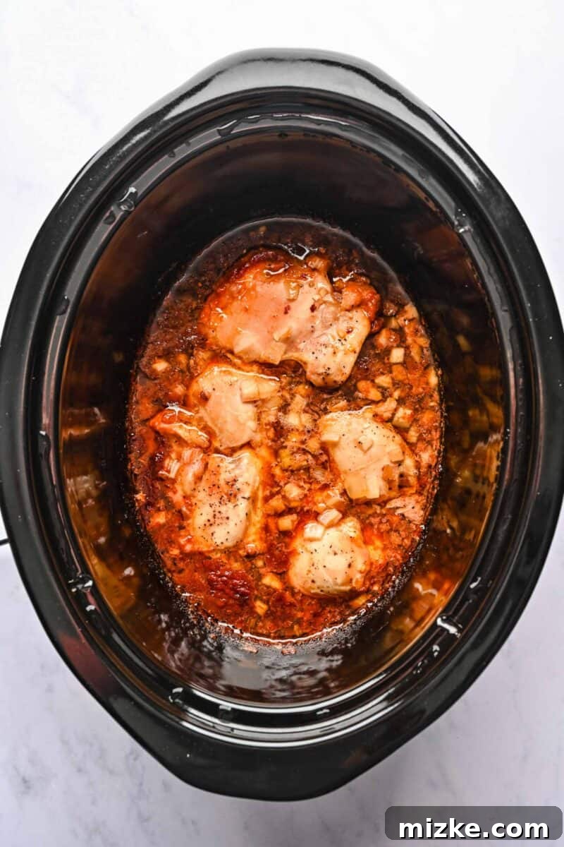 Perfectly Cooked Honey Sesame Chicken in Slow Cooker The honey sesame chicken, perfectly cooked and tender, rests within the crockpot, immersed in its rich, aromatic sauce.