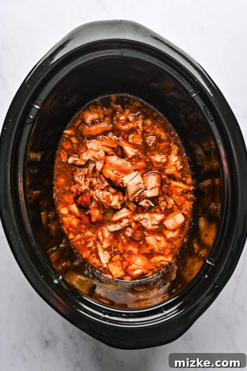 Reincorporating Chopped Chicken with Thickened Sauce Cooked chicken is chopped into bite-sized pieces and returned to the crockpot, where it is thoroughly mixed with the thickened honey sesame sauce.