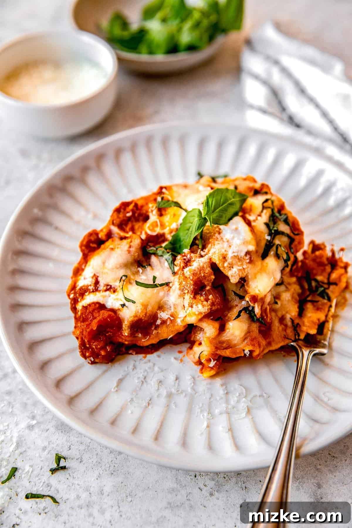 A vibrant serving of skillet lasagna on a white plate, showcasing its tender noodles, rich sauce, and melty cheese.