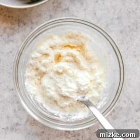 Whisking together ricotta and grated parmesan cheese.