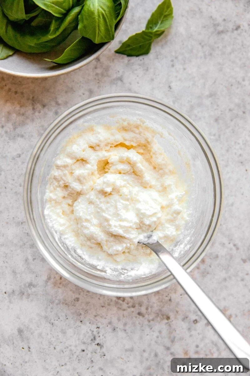 Whisking together ricotta and grated parmesan cheese until smooth.