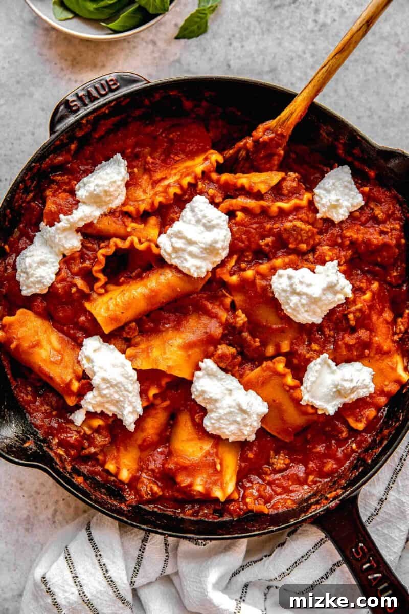 Adding dollops of the ricotta and parmesan cheese mixture to the skillet lasagna.