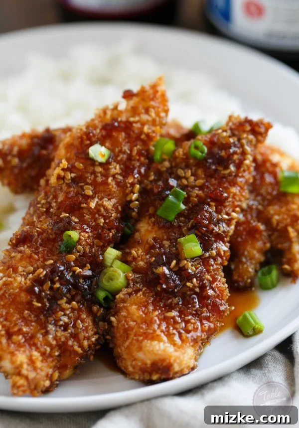 Sweet Heat Crispy Chicken Strips 4 Crispy Sweet and Spicy Chicken Tenders arranged artfully on a plate, ready to be served. Emphasizes the rich color and inviting appeal of the dish.