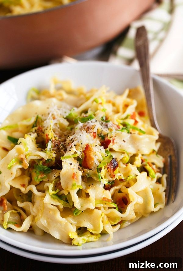 Savory Bacon and Brussels Sprouts Carbonara 4 A close-up of the mafaldine pasta noodles coated in the creamy carbonara sauce with visible bacon and brussels sprouts.