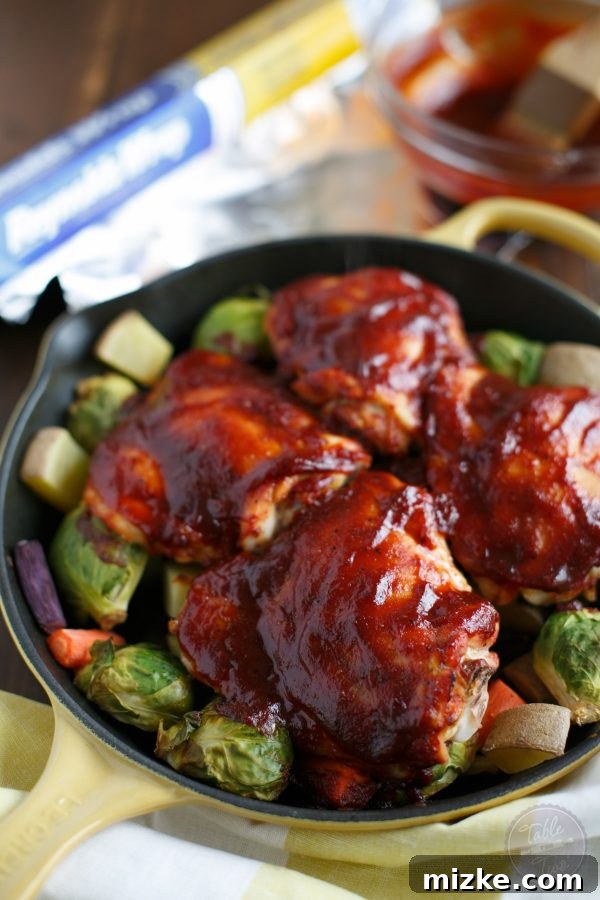 Easy BBQ Chicken and Vegetable Skillet 4 A cast iron skillet filled with colorful BBQ chicken, potatoes, and Brussels sprouts, covered securely with Reynolds Wrap Non-Stick Foil for grilling.