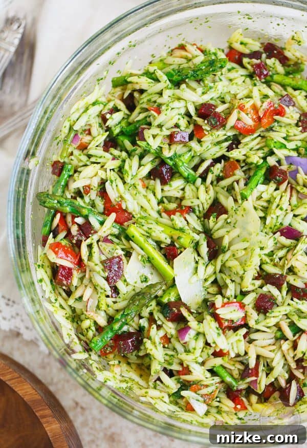 Verde Orzo with Arugula Spinach Pesto 2 A vibrant and colorful springtime pasta salad dish with orzo, asparagus, roasted red peppers, and beets, perfect for outdoor events or home meals.