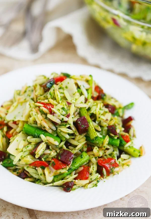 Verde Orzo with Arugula Spinach Pesto 3 Close-up of the vibrant Arugula Spinach Pesto Orzo Salad, showcasing its rich colors and fresh ingredients like orzo, asparagus, and roasted red peppers.