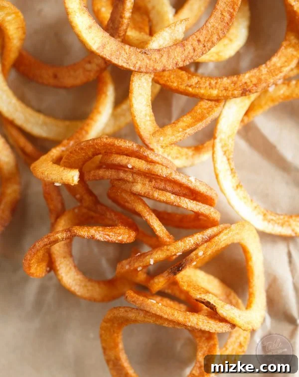 Close-up view of perfectly fried, golden curly fries with a rustic, appetizing texture.